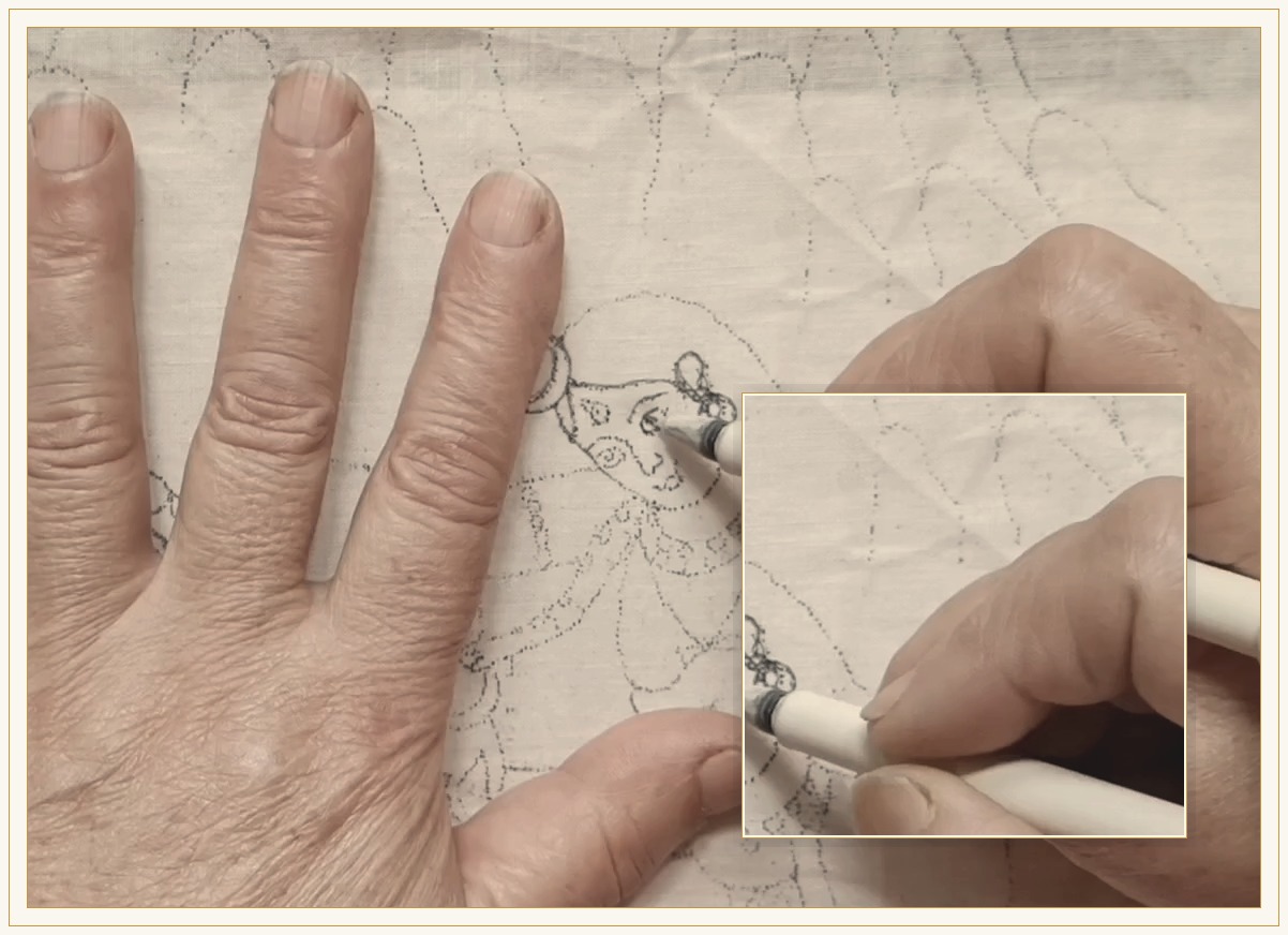 A hand drawing the outline of a composition onto cloth in pencil