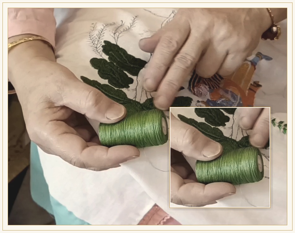 Untwisted silk thread on a spool held in the hand, against embroidered cloth